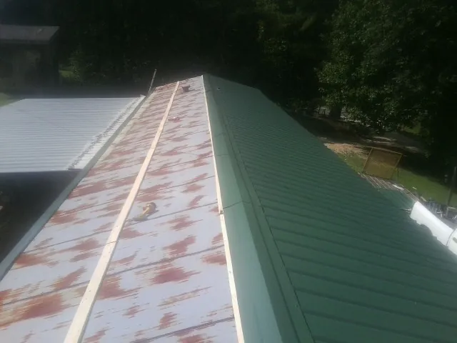 Old rusted panels beside newly installed green metal roofing — Wind Damage Roof Repair by Roofing Brothers in Lake Arrowhead