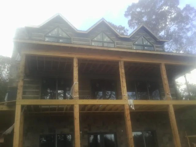 Dormers and porch framing on a large log home under construction — Roof Coating work by our crew in Lake Arrowhead