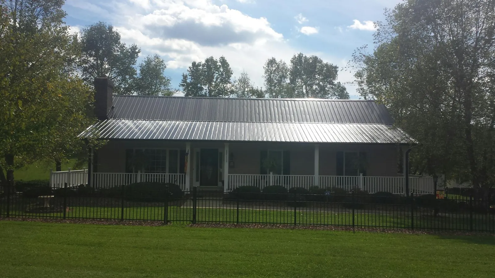 Gray metal roof on a brick ranch with a full width front porch — Gutter Guard Installation work by our crew in Lake Arrowhead