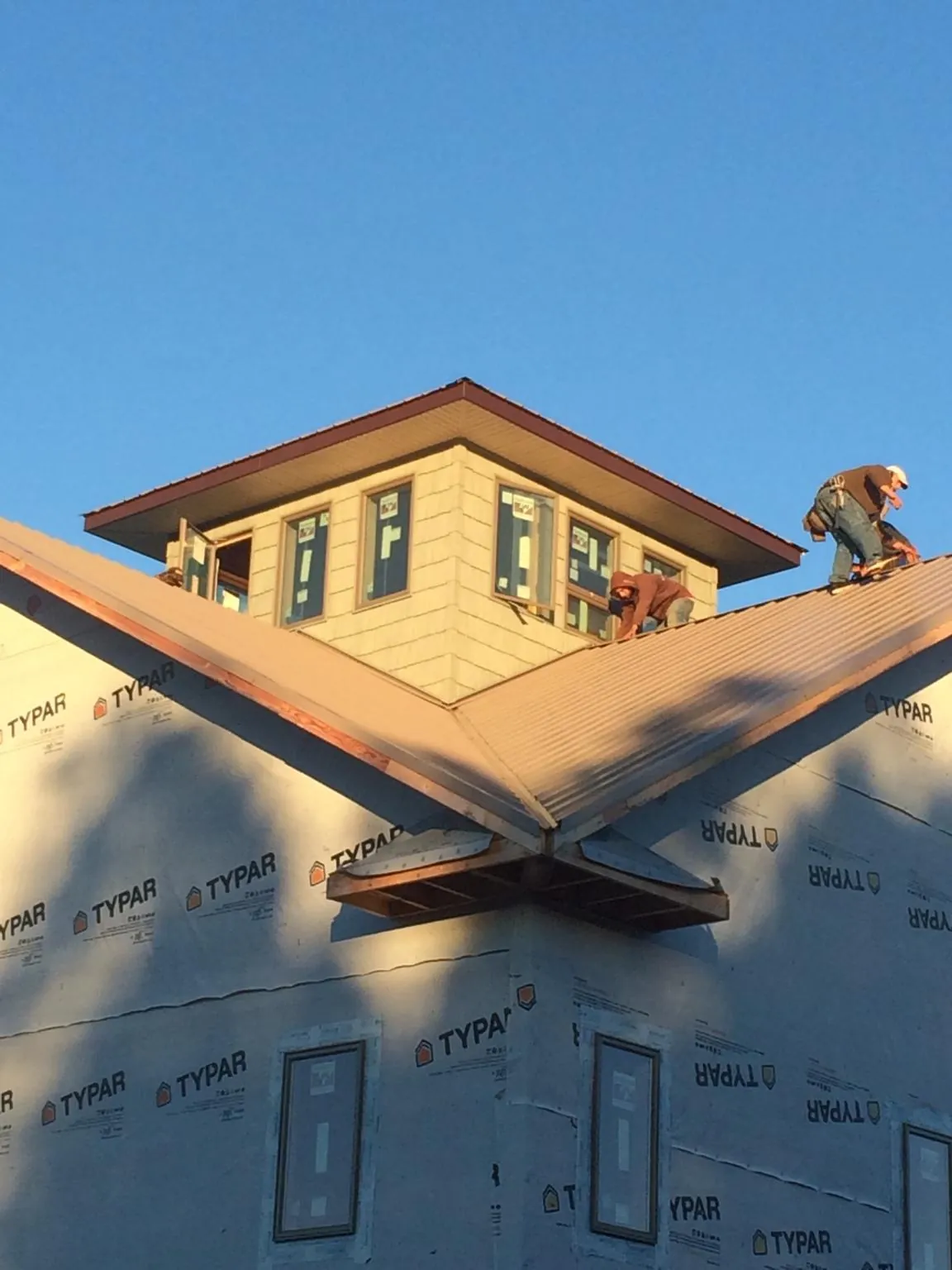 Roofers working around a rooftop cupola on a new metal roof at sunset — Roof Waterproofing in Lake Arrowhead by Roofing Brothers
